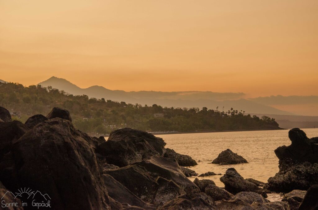 Abendstimmung im Hintergrund der Mount Agung, davor große Steine.